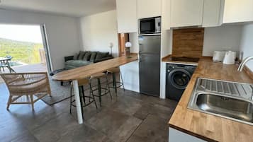 Una cocina moderna con una isla de madera, electrodomésticos de acero inoxidable y lavadora integrada.