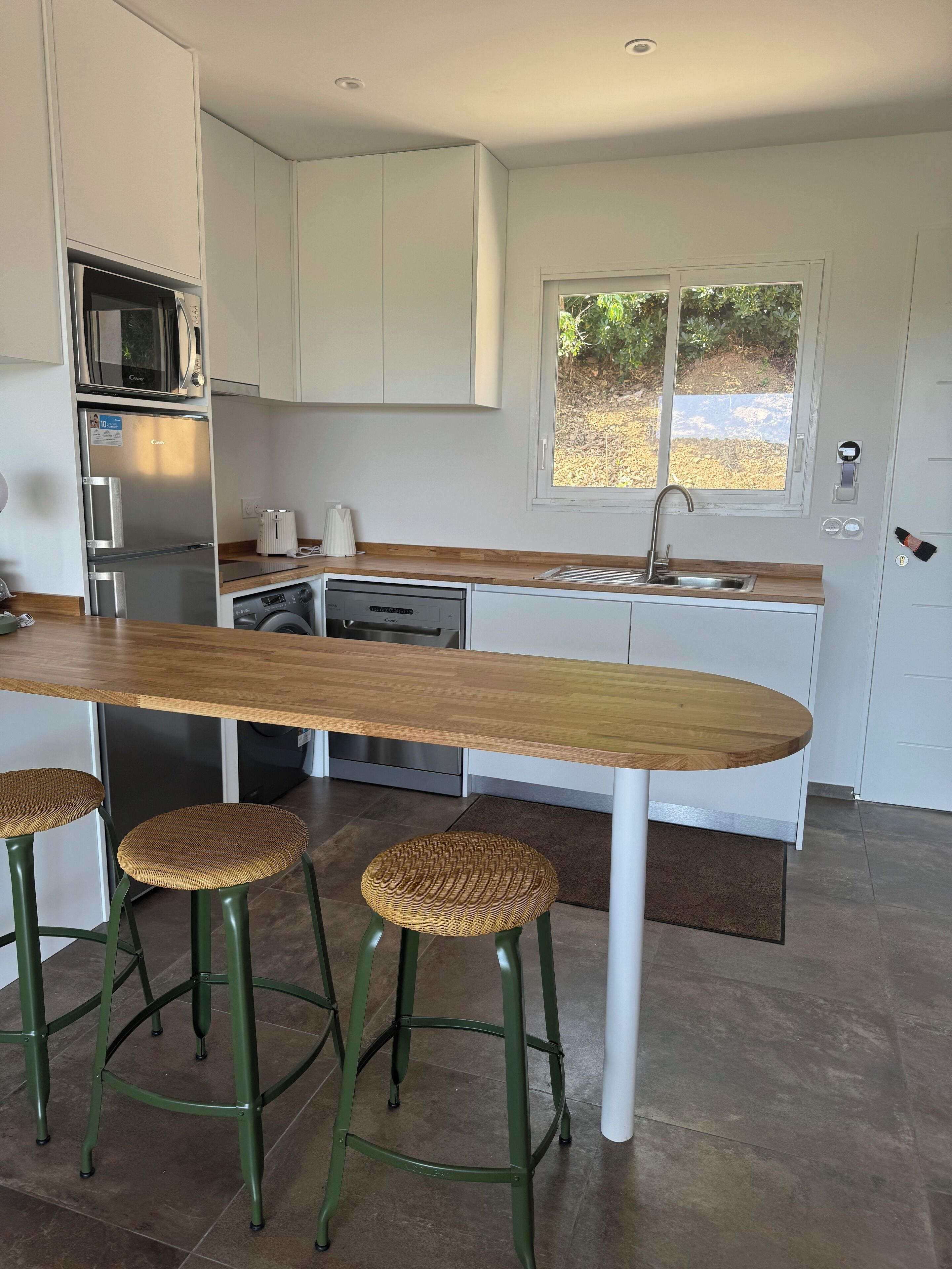 A modern kitchen with a wooden countertop, stainless steel appliances, and a window providing natural light.