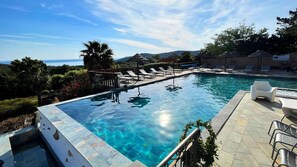 Una piscina al aire libre, sombrillas, sillones reclinables de piscina