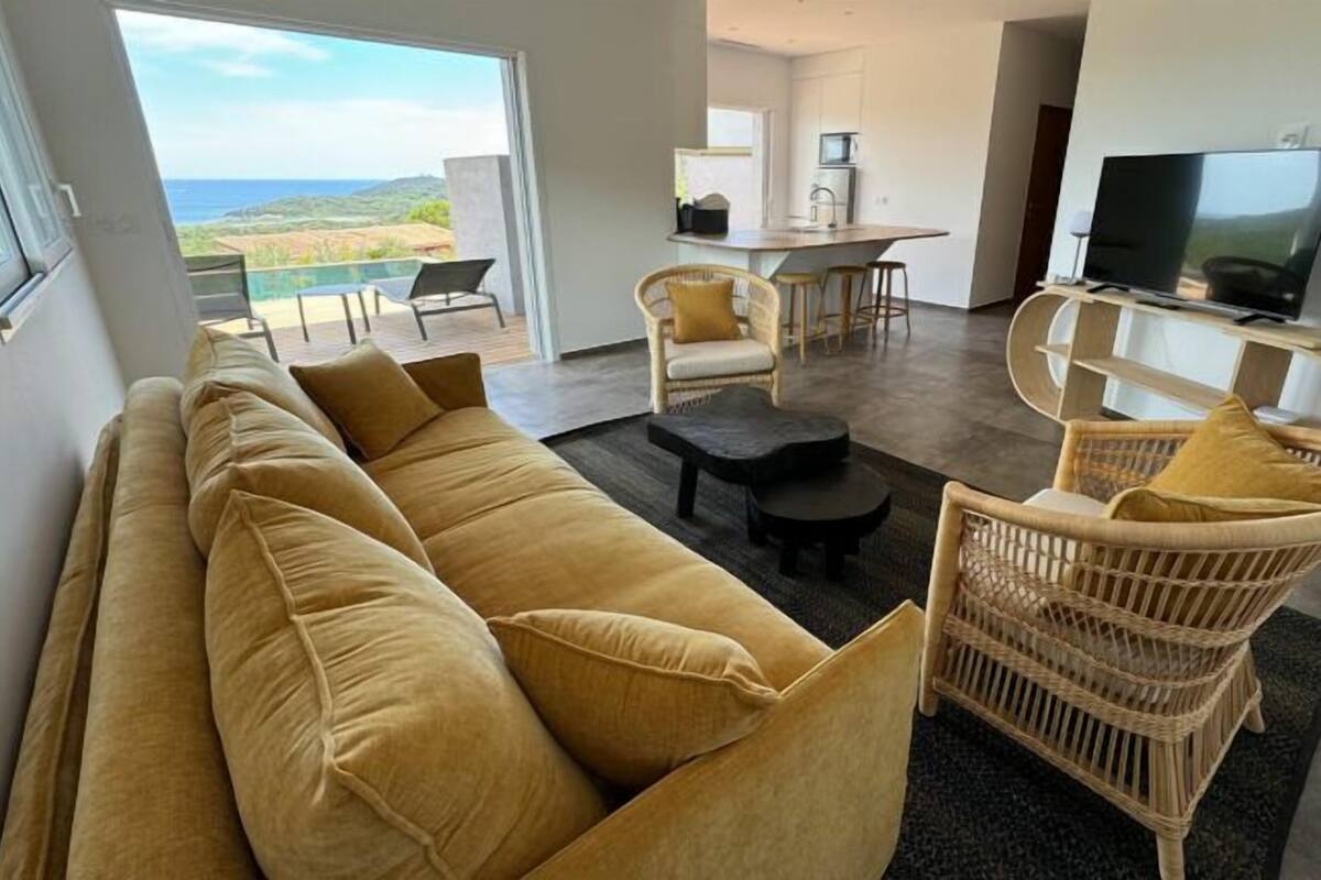 Ein modernes Wohnzimmer mit einer Couch, Sesseln, einem Couchtisch und einem Fernseher.