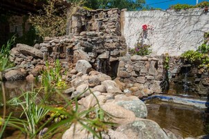 Estructura de cascada de piedra con una pequeña piscina en primer plano.