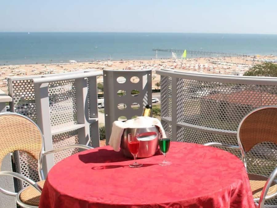 Un balcón con mesa y sillas que da a una playa.