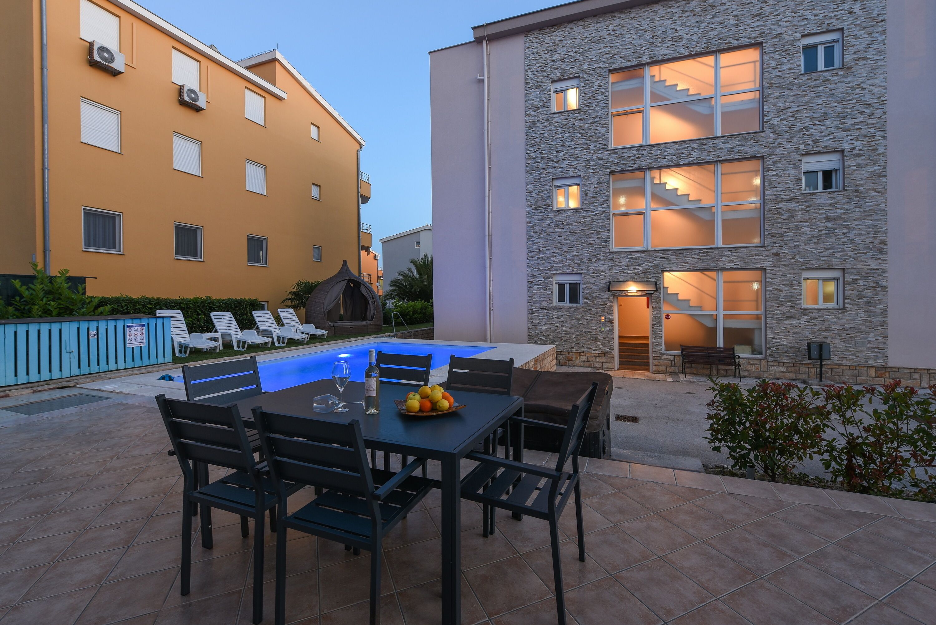 Un patio con piscina, mobiliario exterior y una escalera que lleva a un nivel superior.