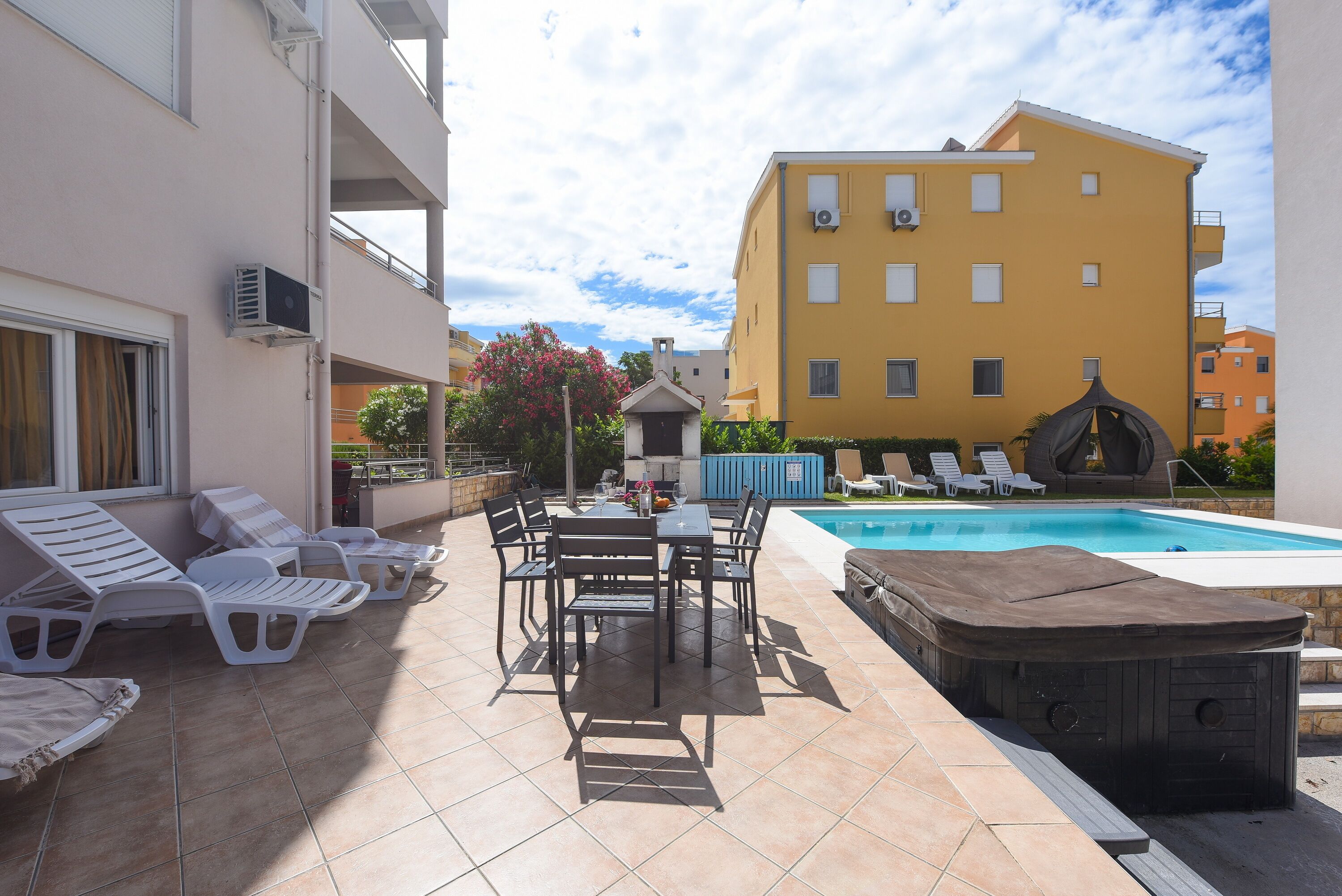 A poolside area with lounge chairs, a hot tub, and a dining table.