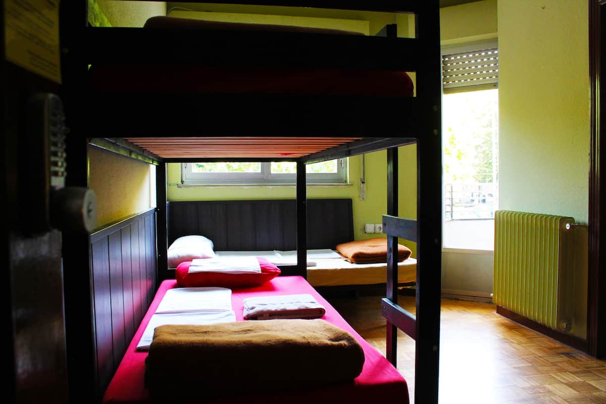 A bunk bed room with two beds, a window, and a radiator.