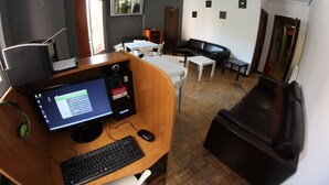 Una habitación con escritorio, computadora y sofá de cuero negro.