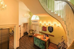 A hotel lobby with a reception desk, a staircase, and a sign for 'The Brooklyn Hotel.' - The Dude Hotel (Berlin)
