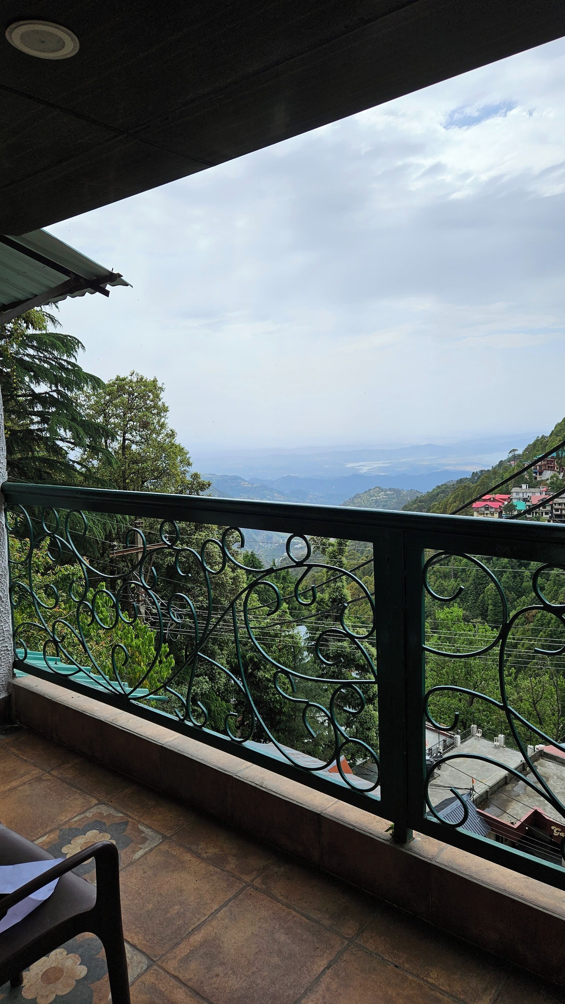 A balcony with a metal railing overlooking a mountainous landscape.