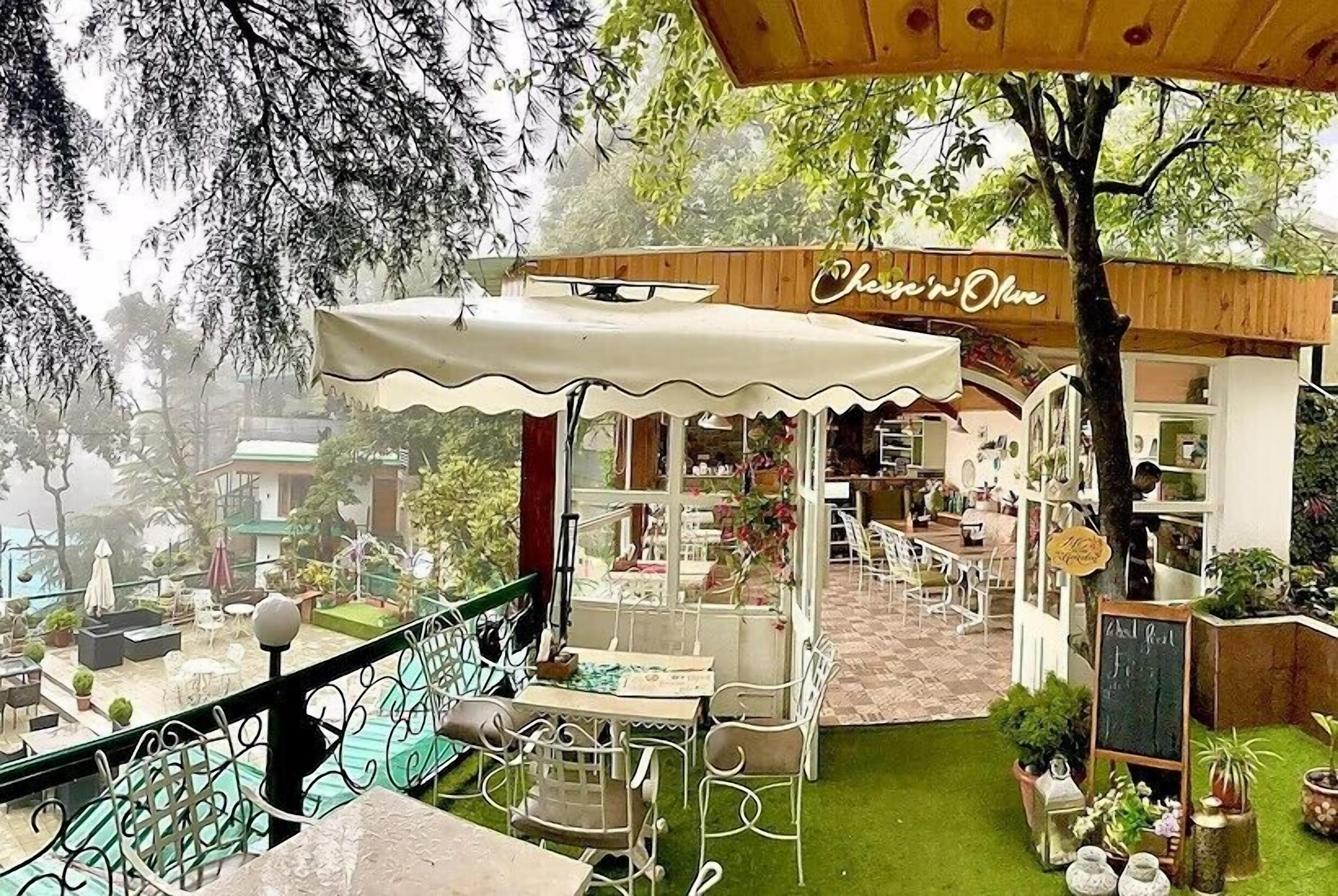An outdoor café with a covered seating area, a wooden fence, and a sign that reads "Chenin' Olio."