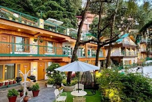 A hotel with a courtyard featuring potted plants, outdoor seating, and a large umbrella.