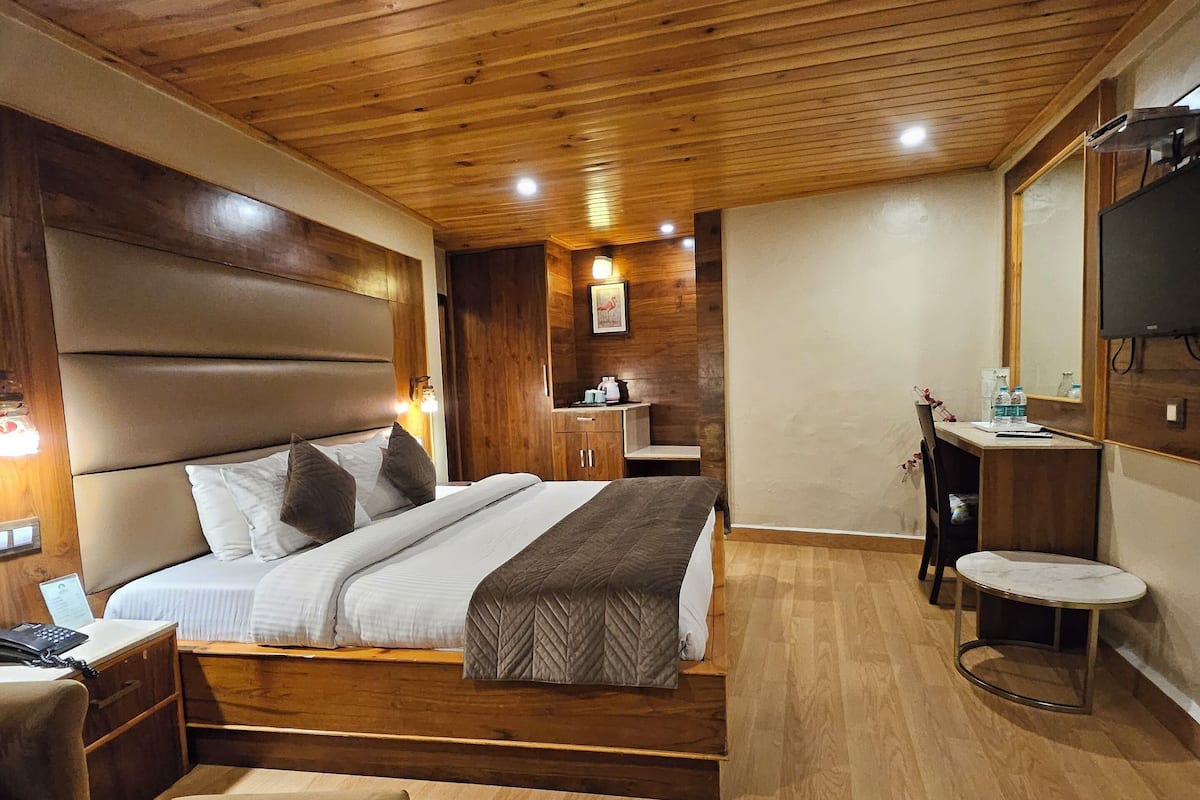 A modern bedroom with a wooden ceiling, a large bed, bedside tables, a desk, and a mirror.