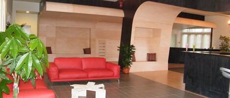 Una sala de estar moderna con un sofá rojo, una mesa de centro blanca y una planta en maceta.