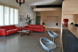 Ein modernes Wohnzimmer mit einem roten Sofa, einem Couchtisch und zwei Barhocker.