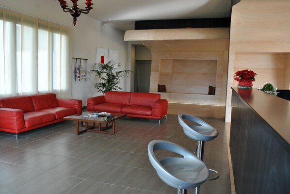Ein modernes Wohnzimmer mit einem roten Sofa, einem Couchtisch und zwei Barhocker.