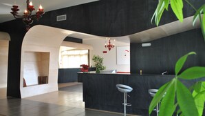 A modern kitchen with dark countertops, a bar area with stools, and a large window providing natural light. - Althea Palace (Castelvetrano)