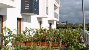 A modern building with multiple balconies, large windows, and a rooftop garden with potted plants. - Althea Palace (Castelvetrano)
