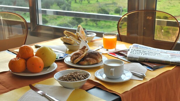 A breakfast table with fruits, pastries, and a newspaper. - Althea Palace (Castelvetrano)