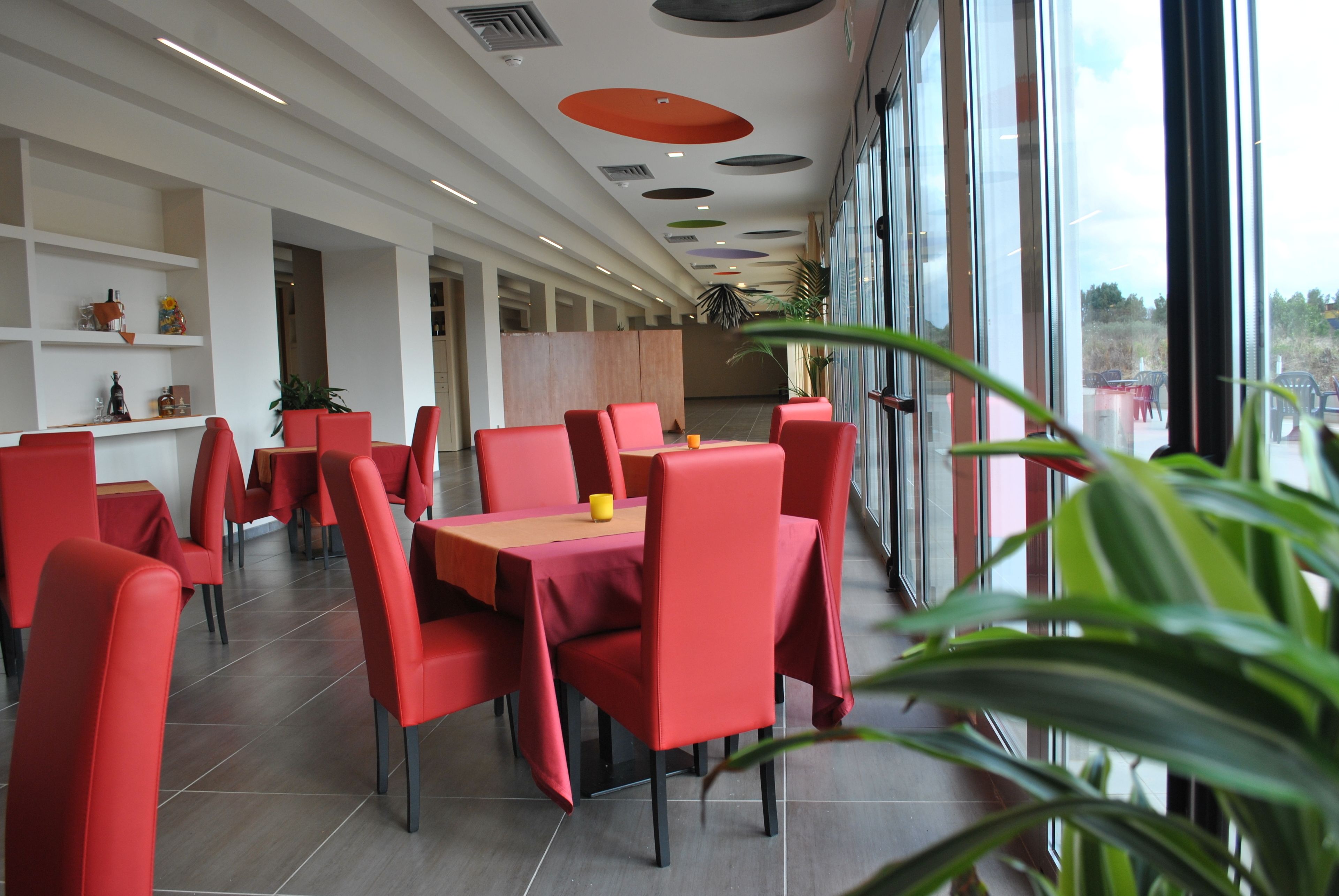 Un ristorante moderno con sedie e tavoli rossi, ampie finestre e vista sull'esterno.