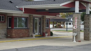 A building with a red and white exterior, a brick foundation, and a sign indicating an office. - Pinconning Trail Inn Motel (Pinconning)