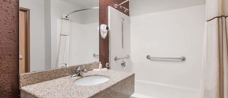 A bathroom with a granite sink, a mirror, a shower with a glass door, and a towel rack.