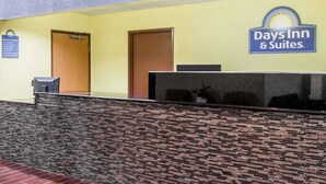 Ett entréområde med en vägg av sten, en receptionsdisk och en skylt för Days Inn & Suites.