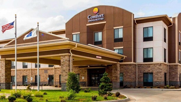 A Comfort Inn & Suites hotel with a covered entrance, brick exterior, and American flag.