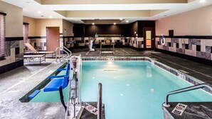 Une piscine intérieure avec un sol carrelé, un plongeoir et un poste de surveillance pour le sauveteur.