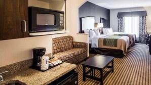 Une chambre d’hôtel équipée d’une kitchenette, d’un canapé, d’un lit et d’une petite table.