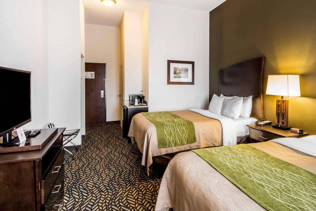 Une chambre d’hôtel avec deux lits, un bureau avec un ordinateur, une télévision et une machine à café.