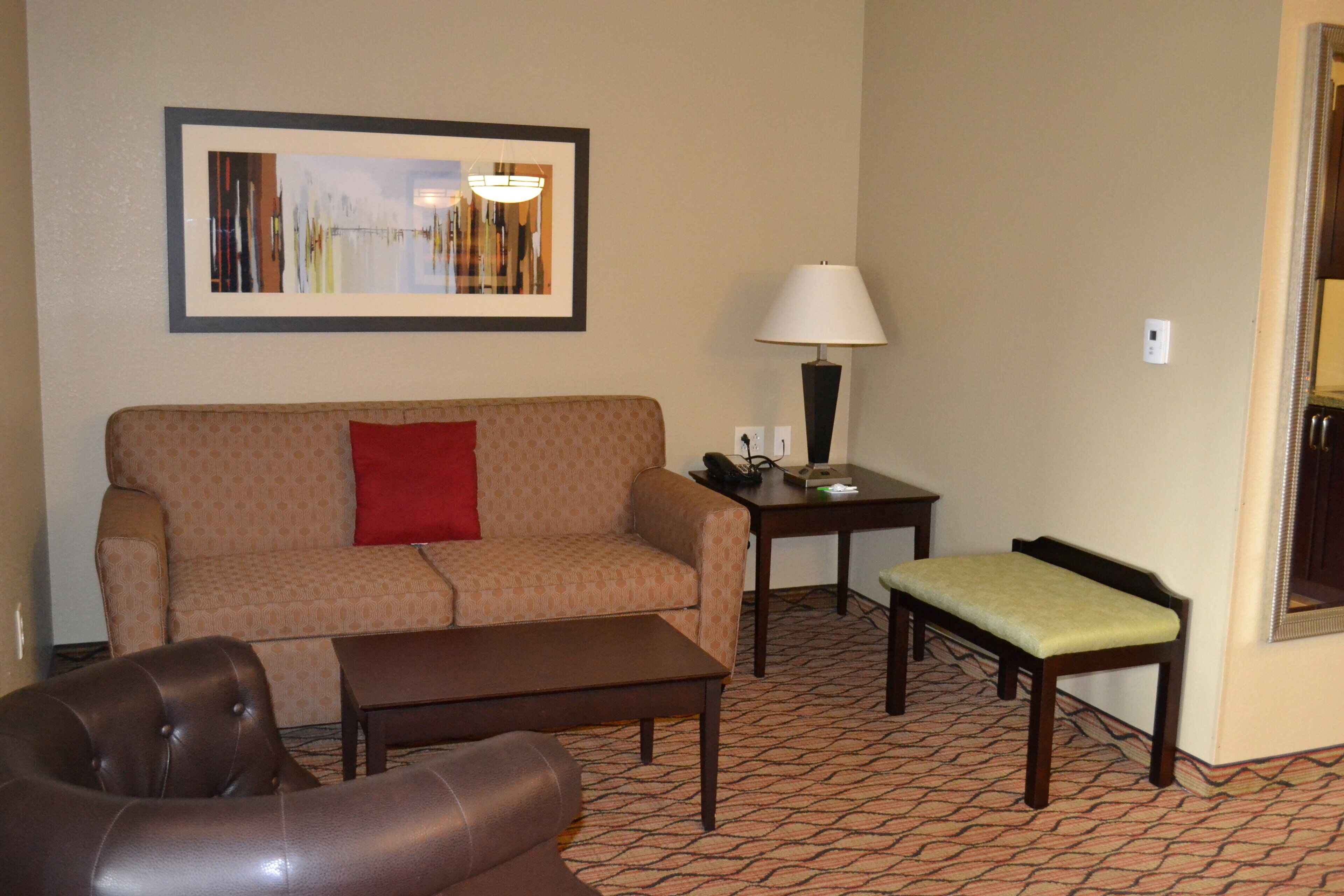 A living room with a sofa, a chair, a small table with a lamp, and a framed picture on the wall.