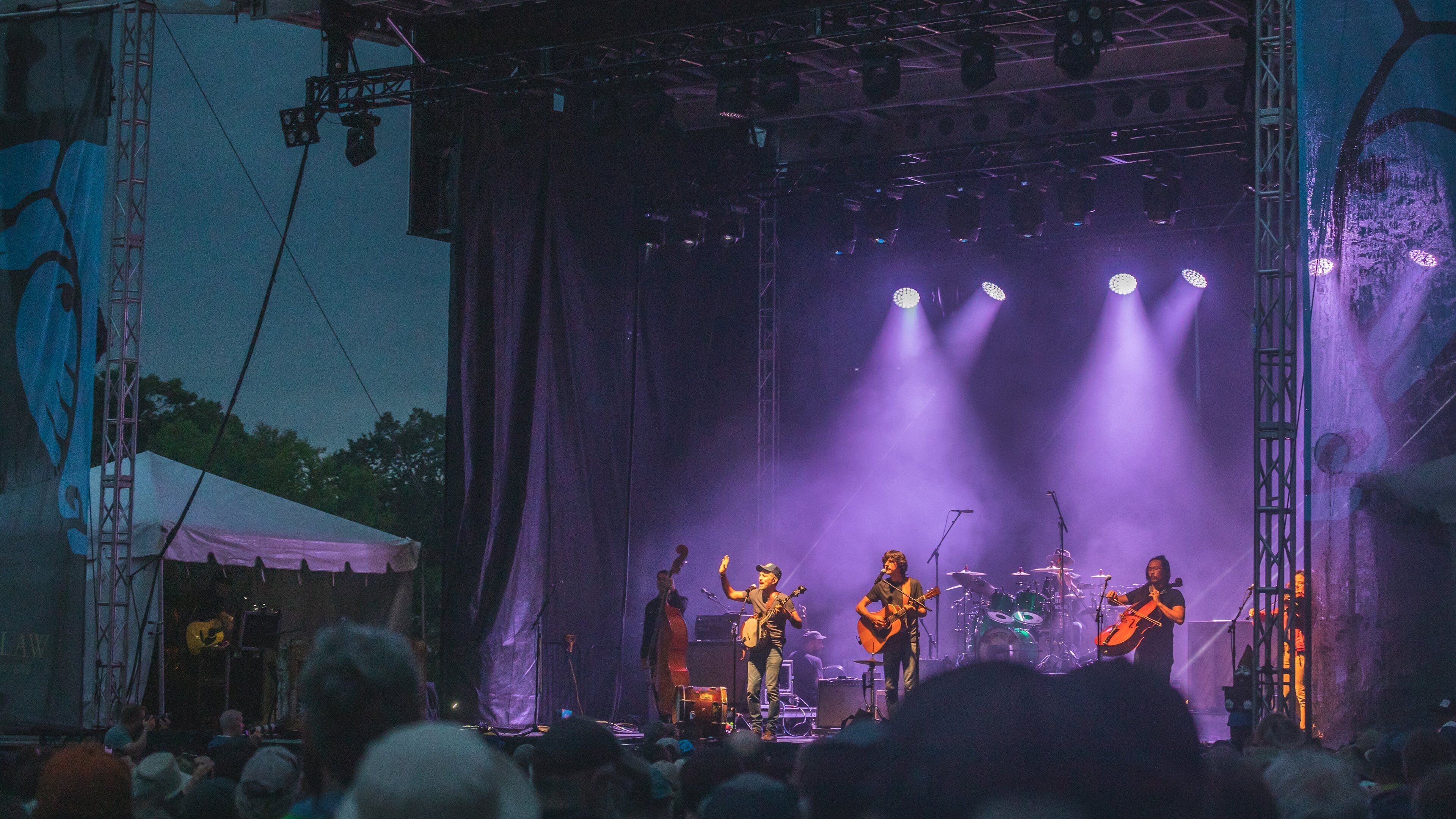 A stage with a band performing, a drum set, and a guitar player.