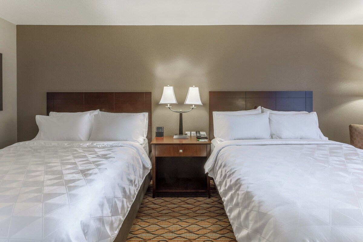 Une chambre d’hôtel avec deux lits, une table de chevet avec des lampes, un téléphone et une petite table.
