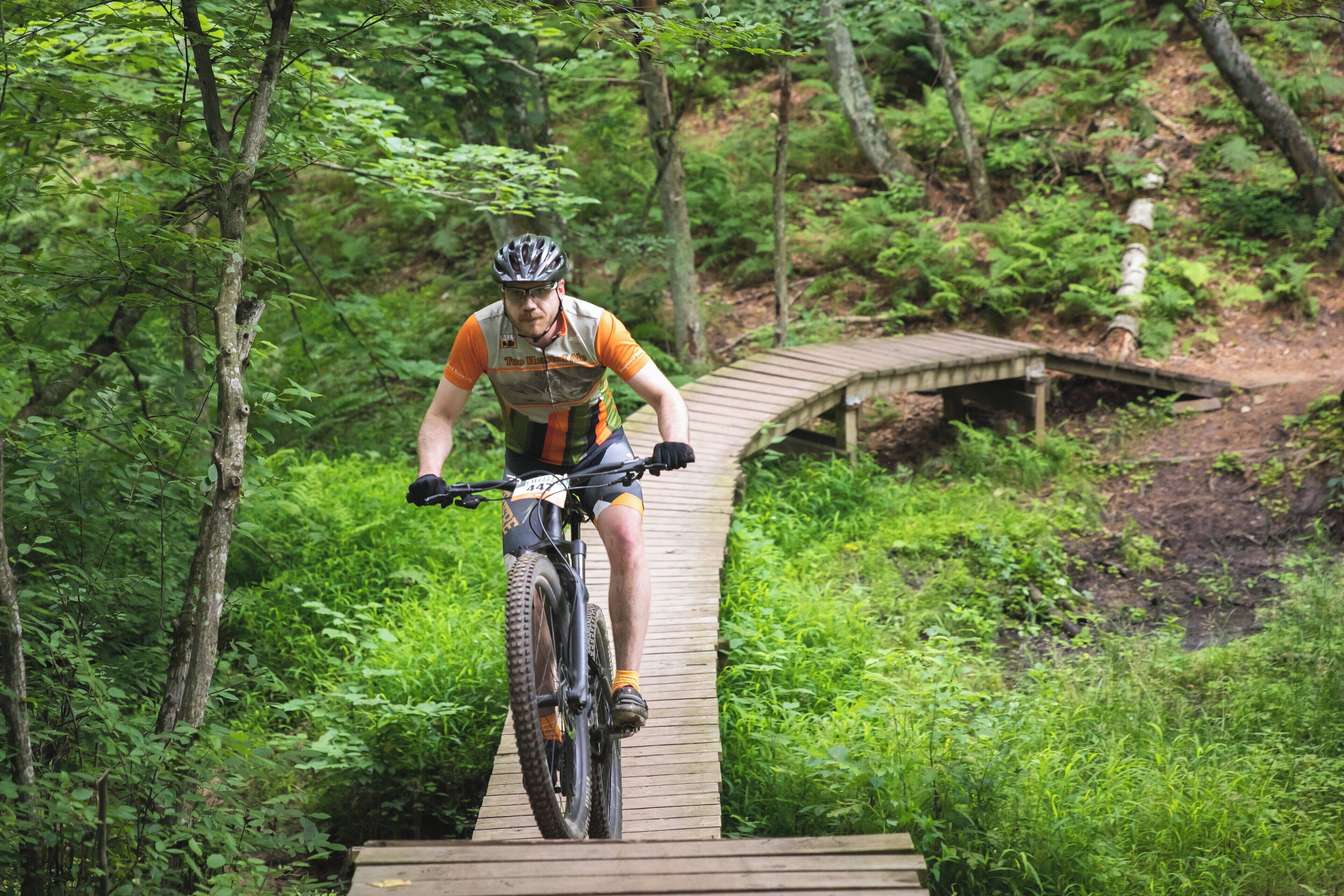 A cyclist on a wooden bridge in a forested area.