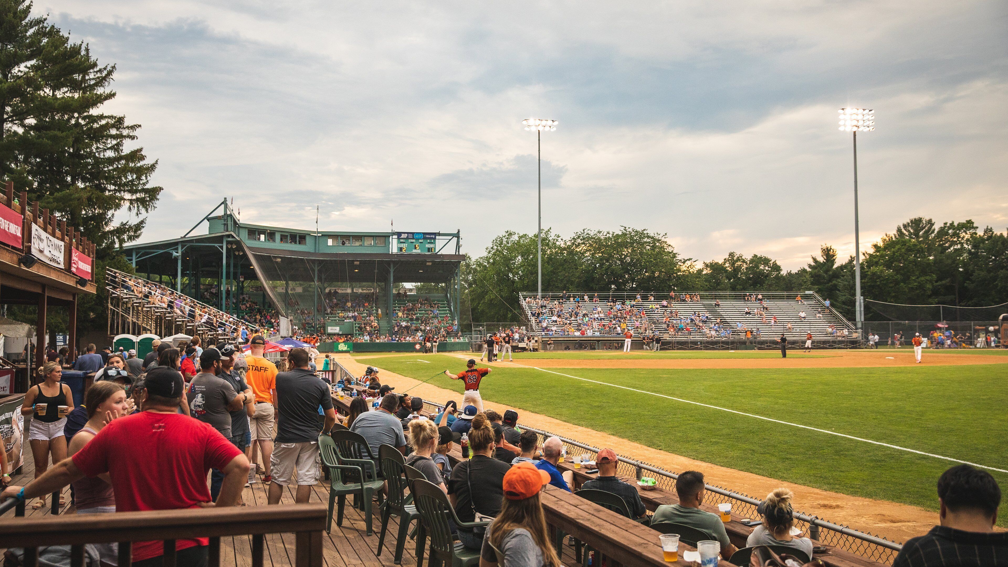 Un estadio de béisbol con asientos en niveles, un campo de juego y un marcador.
