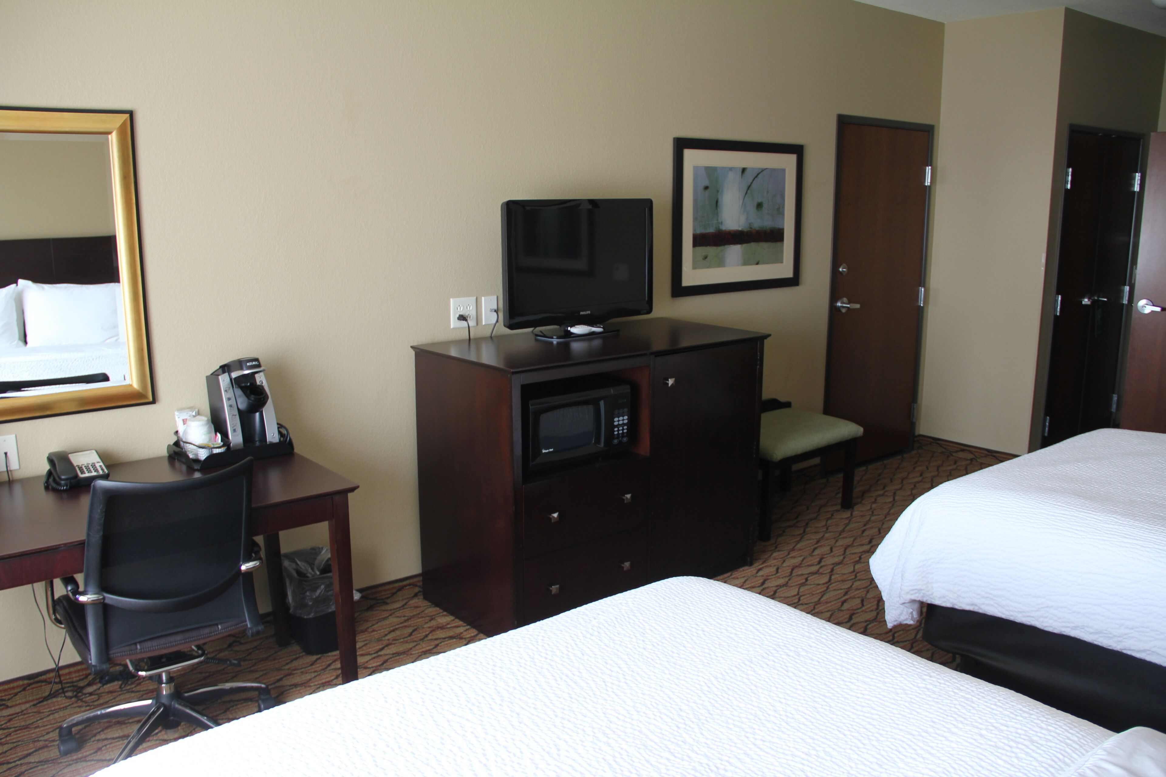 Une chambre d’hôtel équipée d’un lit, d’un bureau avec une chaise, d’une télévision, d’un four à micro-ondes et d’une poubelle.