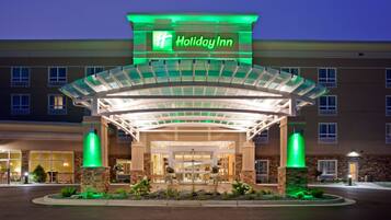 A Holiday Inn hotel with a covered entrance, stone pillars, and a well-lit facade.