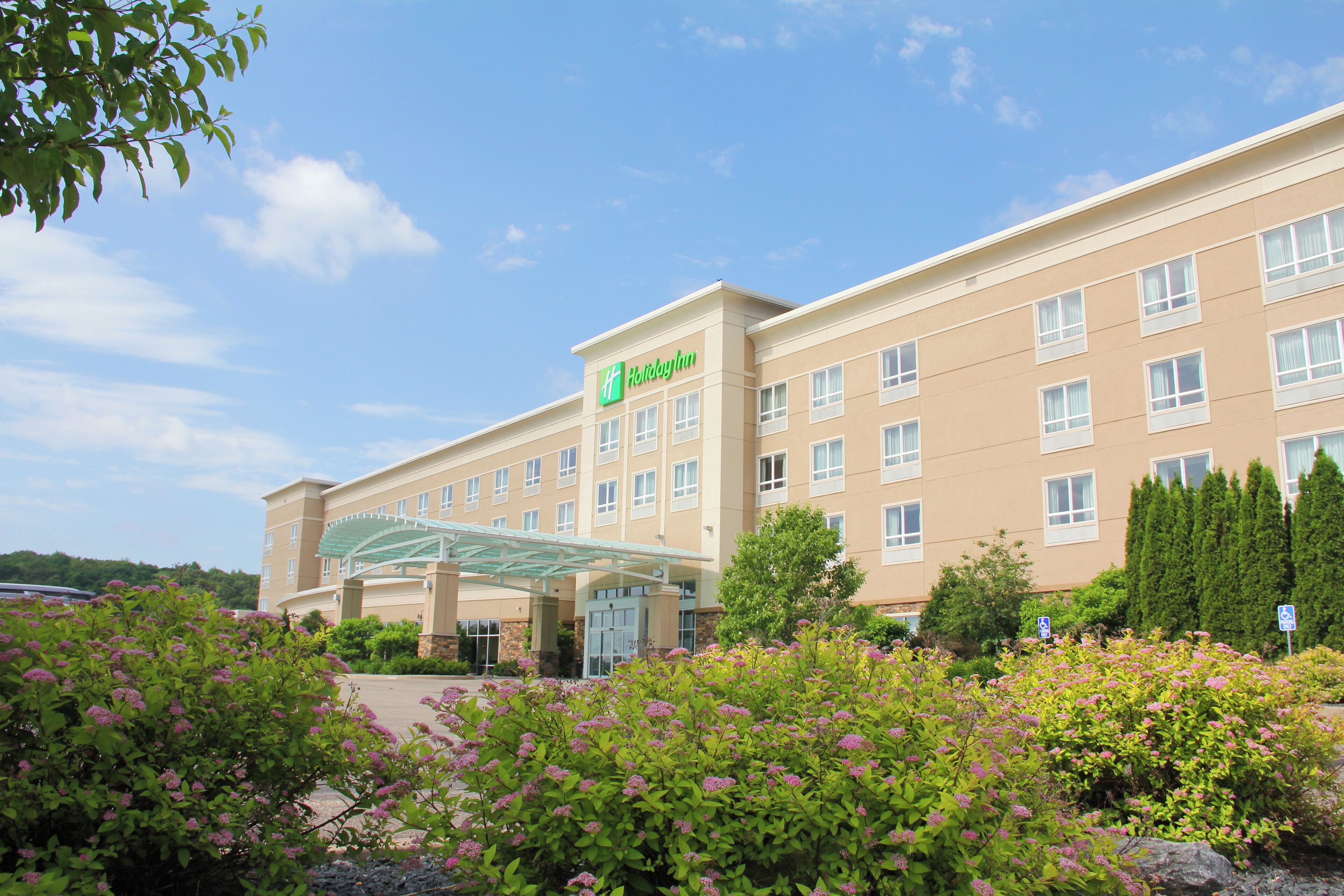 A Holiday Inn hotel with a large building, a covered entrance, and surrounding greenery.