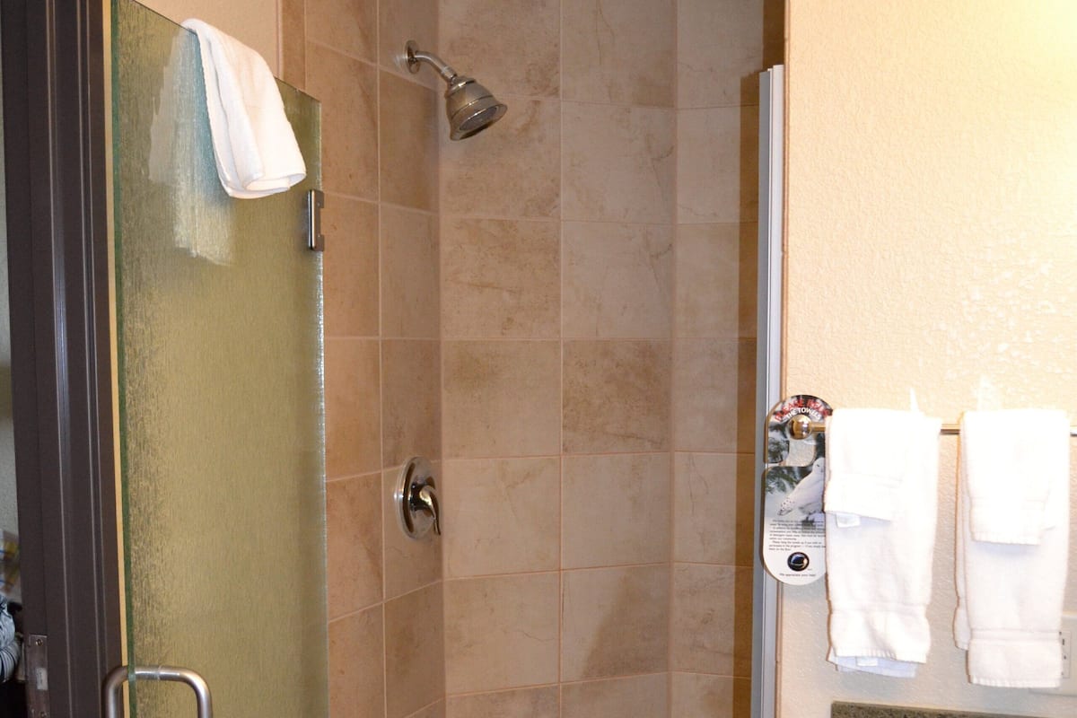 A bathroom with a shower, a sink, and a towel rack.