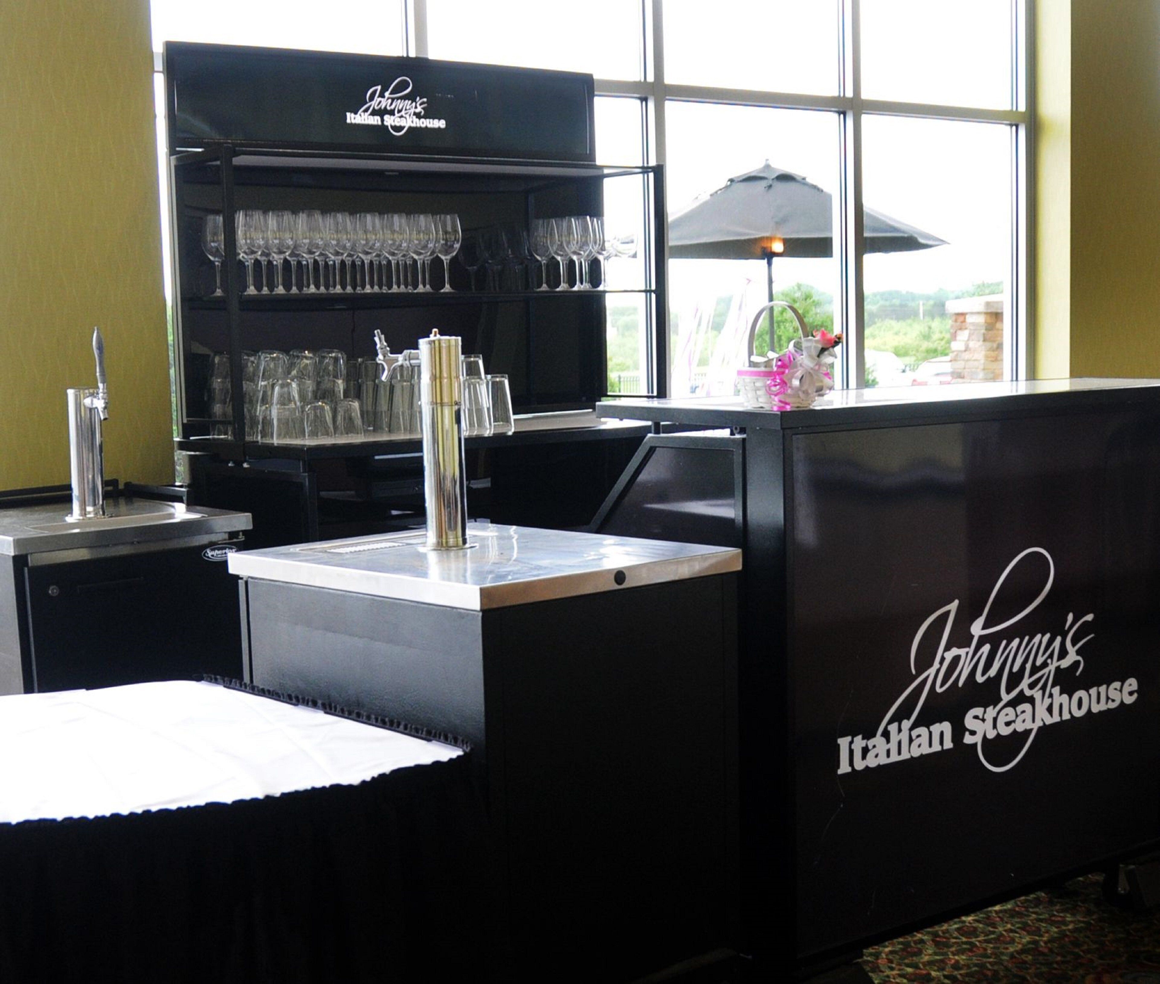 Een bar met een toog, glazen en een bordje met de tekst 'Johnny's Italian Steakhouse'.