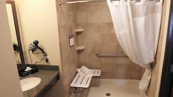 A small, walk-in shower with a white shower curtain, a towel rack, and a hand dryer.
