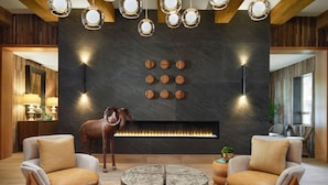 A modern living room with a fireplace, two armchairs, a round coffee table, and a decorative horse statue. - Red Cliffs Lodge Zion, A Tribute Portfolio Hotel - Marriott Bonvoy (Springdale)