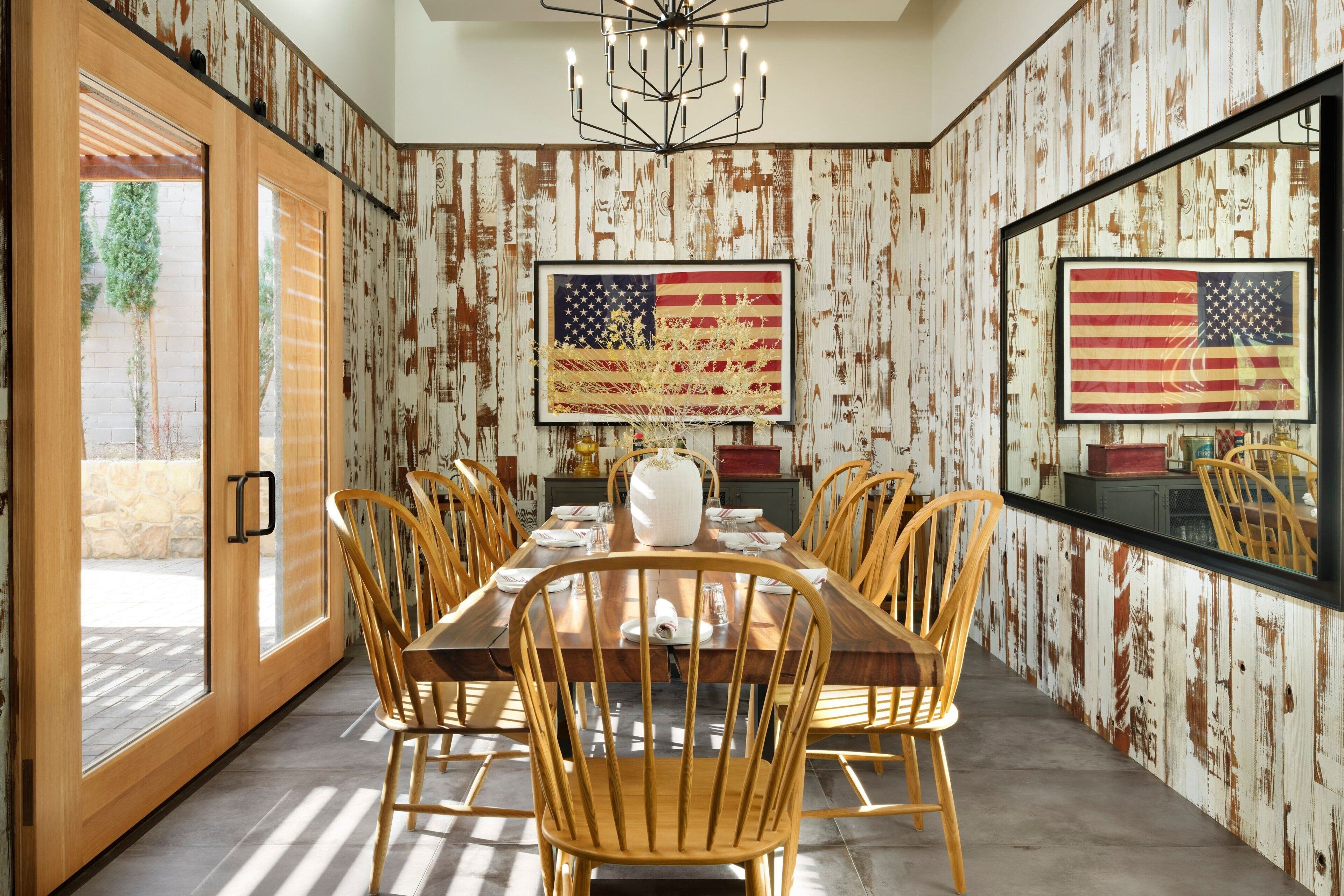 Ein Esszimmer mit einem langen Holztisch, mehreren Stühlen und zwei großen Bildern der amerikanischen Flagge an den Wänden.