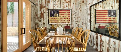 Ein Esszimmer mit einem langen Holztisch, mehreren Stühlen und zwei großen Bildern der amerikanischen Flagge an den Wänden.