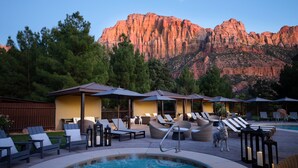 A pool area with lounge chairs and umbrellas, surrounded by a mountainous landscape. - Red Cliffs Lodge Zion, A Tribute Portfolio Hotel - Marriott Bonvoy (Springdale)
