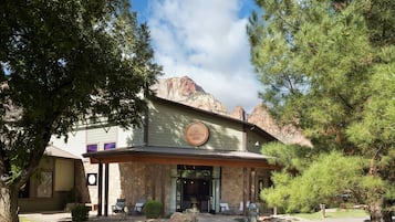 A building with a stone facade, a covered entrance, and outdoor seating.
