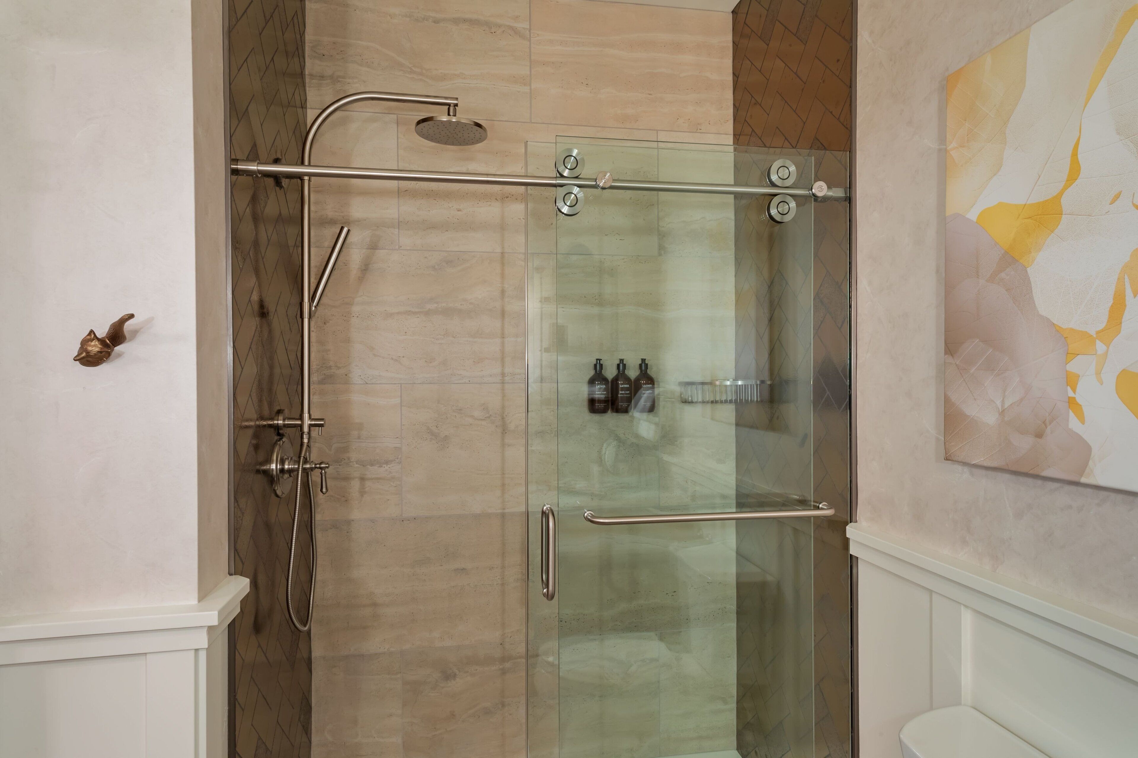 A glass-enclosed shower with a handheld showerhead and a handheld shower attachment.