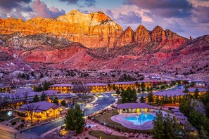 A resort with multiple buildings, a swimming pool, and a mountainous backdrop.