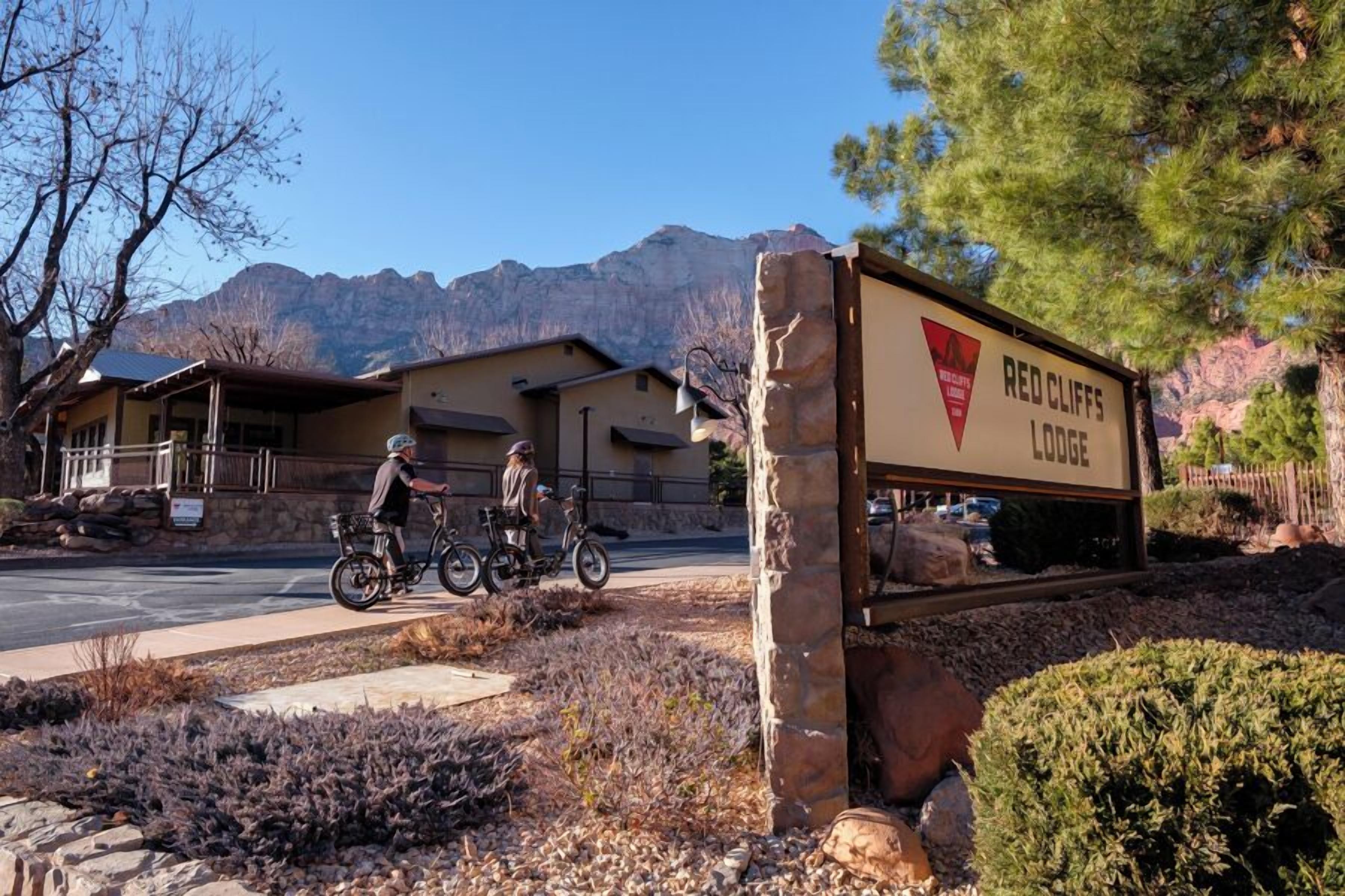 A sign for Red Cliffs Lodge with a mountain backdrop.