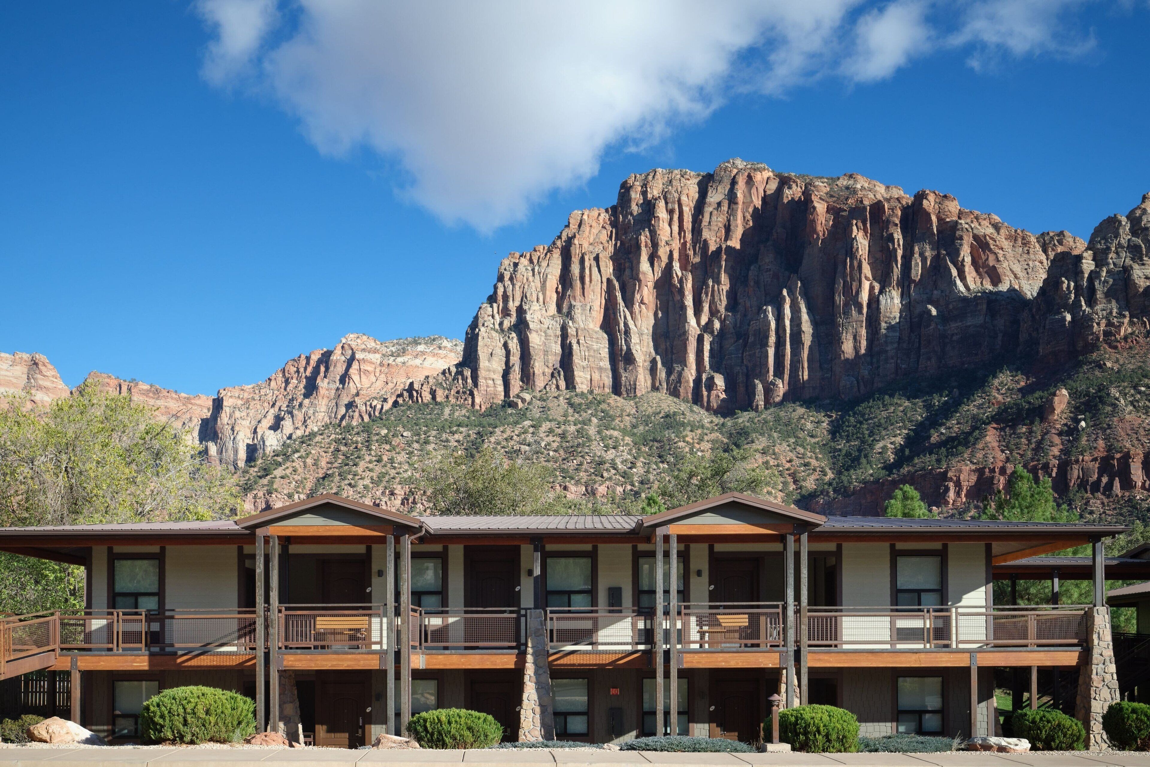 Un hôtel à l’architecture à deux étages, doté de nombreux balcons et offrant une vue sur une chaîne de montagnes.