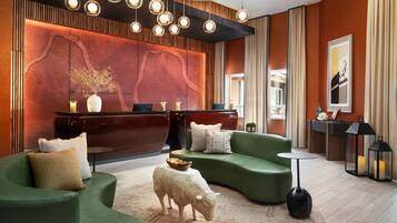 A modern lobby with green sofas, a reception desk, and a decorative sheep sculpture.